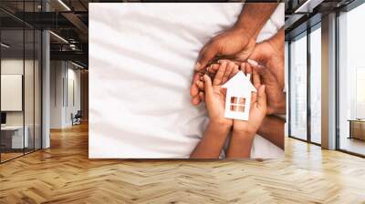 Black family of three holding paper house figure in hands Wall mural