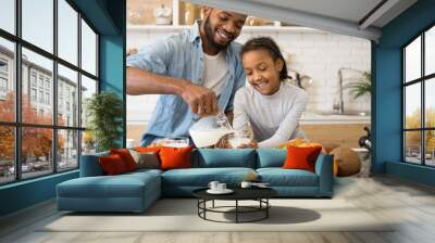 Black father pouring milk into his daughter cup Wall mural