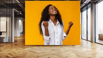 Black girl smiling and raising clenched fists in the air Wall mural