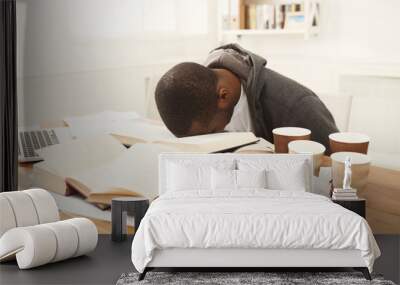 Black male student studying at table full of books Wall mural