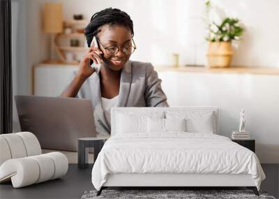 Black Millennial Businesswoman Talking On Cellphone And Taking Notes While Working On Laptop In Modern Office, Selective Focus Wall mural