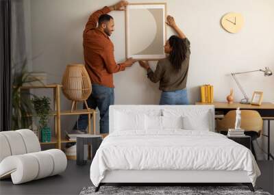 Black Millennial Spouses Hanging Poster On Wall Together At Home Wall mural