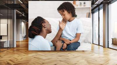 Black mom caressing her depressed kid on sofa Wall mural