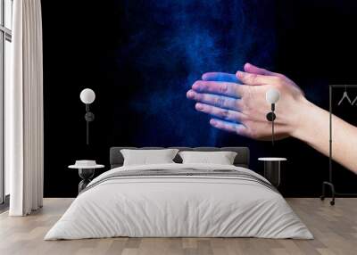 Blue powder splatted from woman hands on black background Wall mural