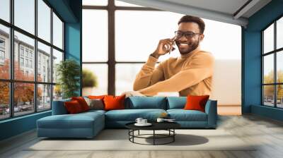 Calling Family. Cheerful black guy making phone call to his relatives or girlfriend at office. Free space Wall mural