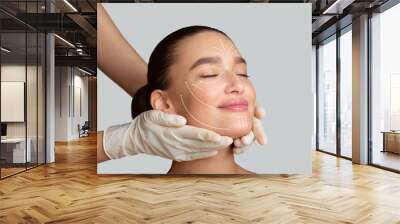 Calm girl receiving face massage from cosmetologist Wall mural