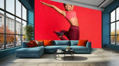 Carefree athletic girl in sportswear happily jumping up Wall mural