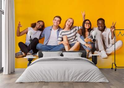 Carefree teenagers having fun over yellow studio background Wall mural