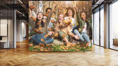 Carefree young friends taking photos with autumn leaves in park Wall mural