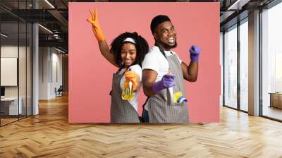 Cheerful african american couple with spray detergents posing on pink background Wall mural