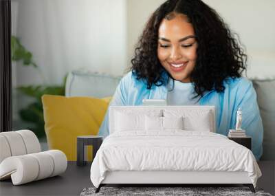 Cheerful African American Woman Using Smartphone Sitting At Home Wall mural