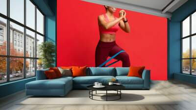 Cheerful afro fitness girl making working out with resistance band Wall mural