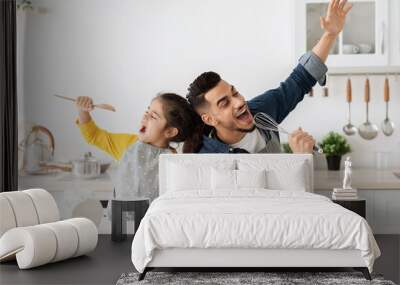 Cheerful arab father and little daughter having fun while baking in kitchen Wall mural