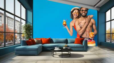 Cheerful black couple in sunglasses and hats drinking summer cocktails Wall mural