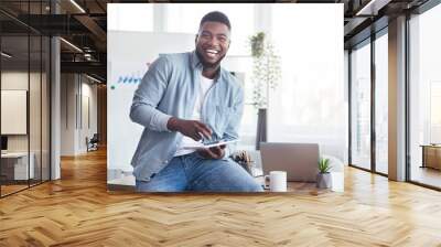 Cheerful black employee using digital tablet in office and laughing Wall mural