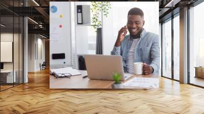 Cheerful black manager talking on mobile phone and drinking coffee Wall mural