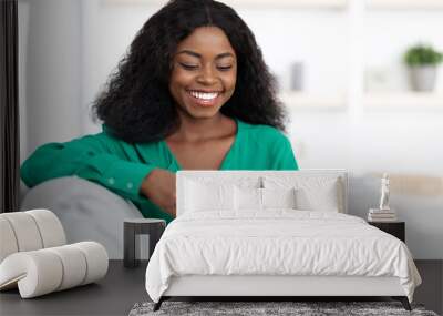 Cheerful black woman chilling at home with smartphone Wall mural