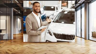 Cheerful Car Dealer Gesturing Showing Brand-New Automobile Standing In Delarship During Luxury Auto Exhibition. Empty Space Wall mural