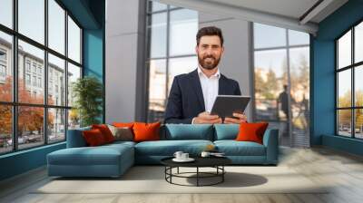 Cheerful confident attractive young european male ceo manager with beard in suit typing on tablet Wall mural