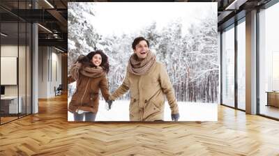 Cheerful Couple Walking Through Winter Forest Holding Hands Wall mural