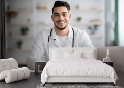 Cheerful doctor arab man working from home, using laptop Wall mural