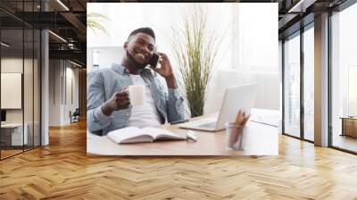 Cheerful employee talking on phone and holding cup with coffee Wall mural