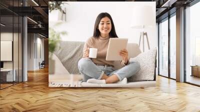 Cheerful girl reading e-book on digital tablet Wall mural