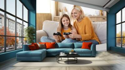 Cheerful girl showing grandma how to play video games Wall mural