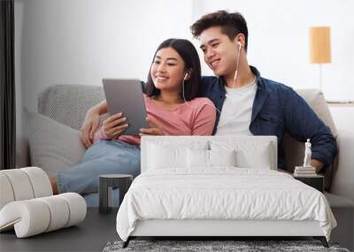 Cheerful Korean Couple Using Digital Tablet Computer Sitting At Home Wall mural