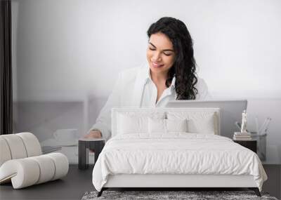 Cheerful latin girl using touchpad with smile at working place Wall mural