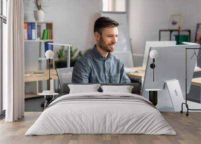 Cheerful middle aged businessman sitting at worktable, typing on computer keyboard, working on marketing research Wall mural