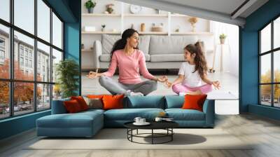 Cheerful mother and daughter meditating together at home Wall mural