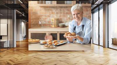 Cheerful old lady posing with freshly baked pastry in kitchen Wall mural