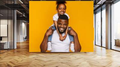 Cheerful portrait of black dad and daughter over yellow background Wall mural