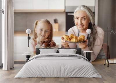 Cheerful pretty little girl and mature grandma in aprons show homemade fresh cookies and croissants Wall mural