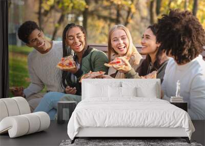 Cheerful students having break at park, eating pizza Wall mural