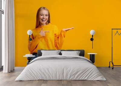 Cheerful teen girl demonstrate something on her empty palm Wall mural