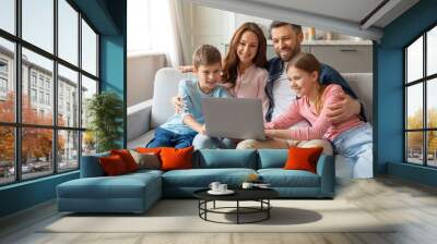 Cheerful young family with kids having fun with laptop at home Wall mural