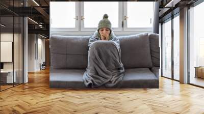 Cold Home. Woman Covered With Blanket Freezing On Couch In Living Room Wall mural