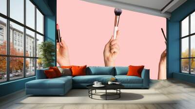 Collection of different makeup products in female hands, collage on pink background Wall mural