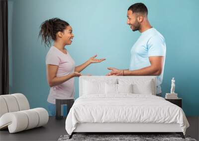 Communication. Profile portrait of black woman and man talking and gesturing over blue studio background Wall mural