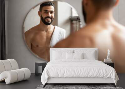 Confident young Arab guy looking in the mirror Wall mural