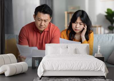 Confused asian couple checking bills, home interior Wall mural