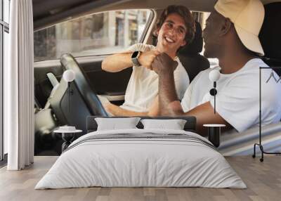 Cool multiethnic guys sitting inside car, giving fist bump Wall mural