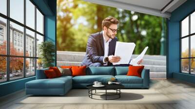 Corporate employee working with business papers on stone stairs in city park Wall mural