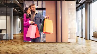 couple with New Year sale bags exploring outdoor mall shops Wall mural