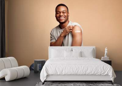 Covid-19 Vaccinated African Man Showing Arm With Plaster, Beige Background Wall mural