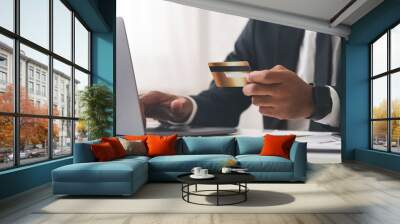 Cropped photo of businessman using laptop and holding credit card Wall mural