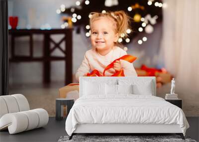 Curious little girl opening xmas gift at home Wall mural