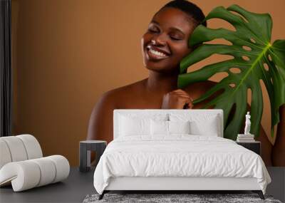 curvy black woman with closed eyes holding monstera leaf Wall mural